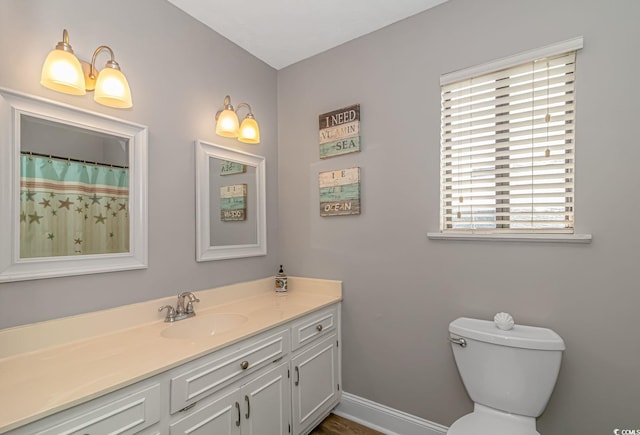 bathroom with toilet, vanity, and baseboards