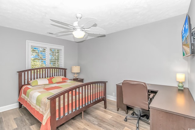 bedroom featuring a ceiling fan, light wood-type flooring, visible vents, and baseboards