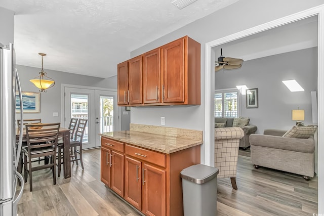 kitchen featuring french doors, light wood-style flooring, freestanding refrigerator, open floor plan, and light stone countertops