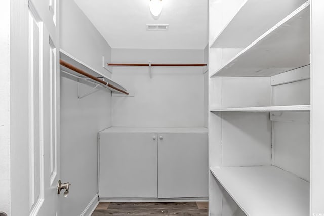 spacious closet with dark wood-style floors and visible vents