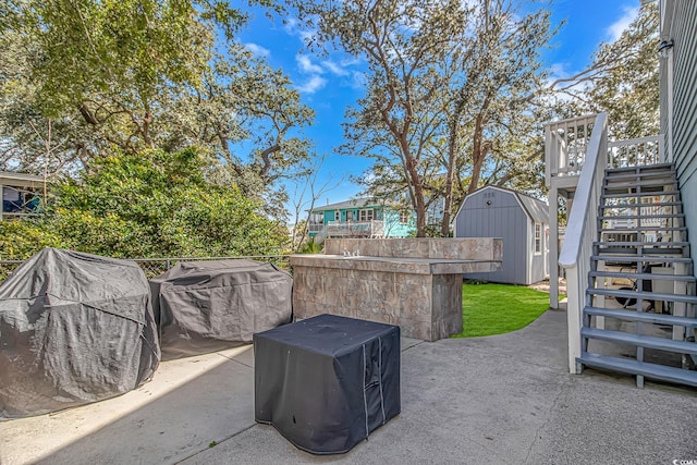 view of patio featuring a storage shed, stairway, and an outbuilding