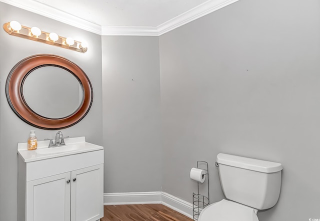 half bath featuring crown molding, toilet, vanity, wood finished floors, and baseboards