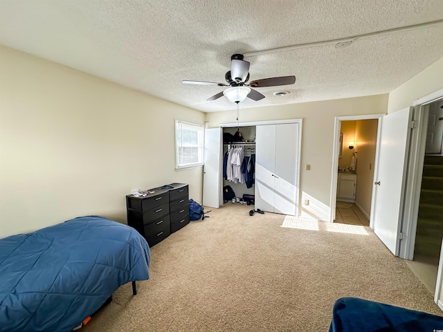 bedroom featuring a textured ceiling, light colored carpet, a closet, and ceiling fan