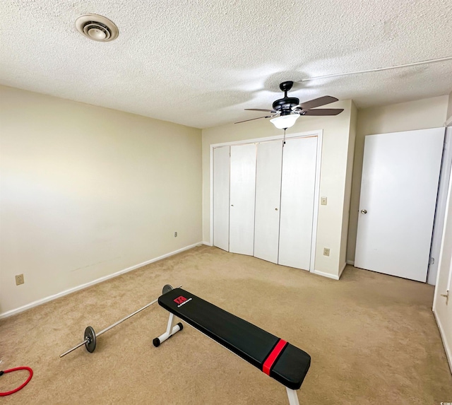 workout area with a ceiling fan, baseboards, visible vents, a textured ceiling, and carpet flooring