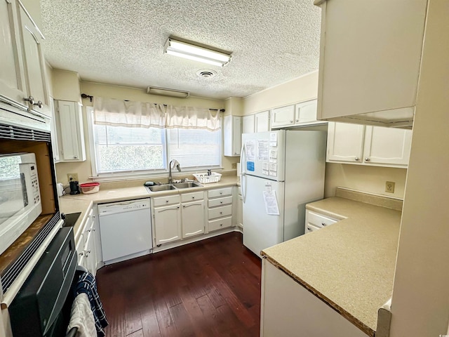 kitchen featuring visible vents, dark wood-style floors, white appliances, white cabinetry, and a sink