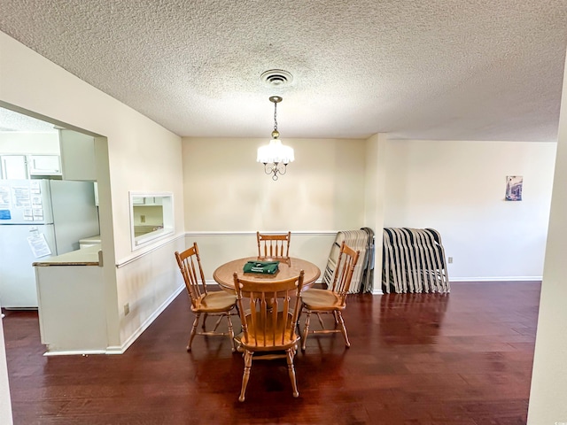 dining area with visible vents, a textured ceiling, wood finished floors, baseboards, and a chandelier