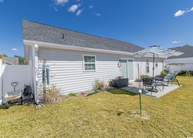 rear view of house with a shingled roof, a yard, fence, and a patio