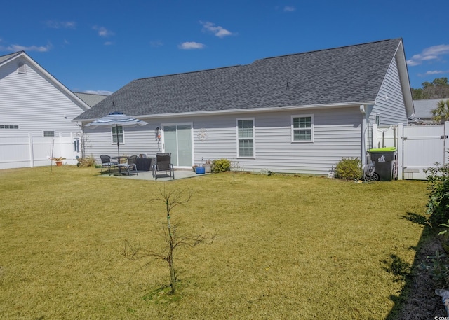 rear view of property featuring a patio area, a shingled roof, fence, and a lawn