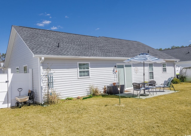 back of house with roof with shingles, a lawn, a patio, and fence