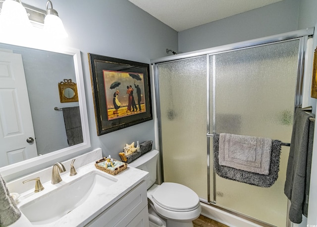 bathroom featuring vanity, a shower stall, and toilet