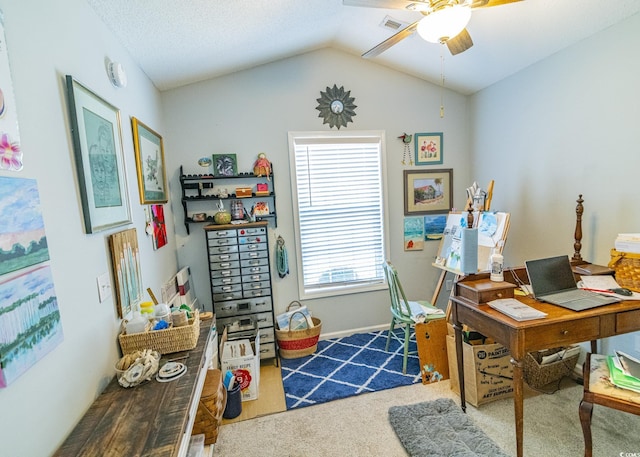 carpeted office with visible vents, vaulted ceiling, and a ceiling fan