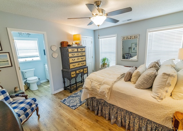 bedroom with multiple windows, visible vents, light wood finished floors, and a textured ceiling