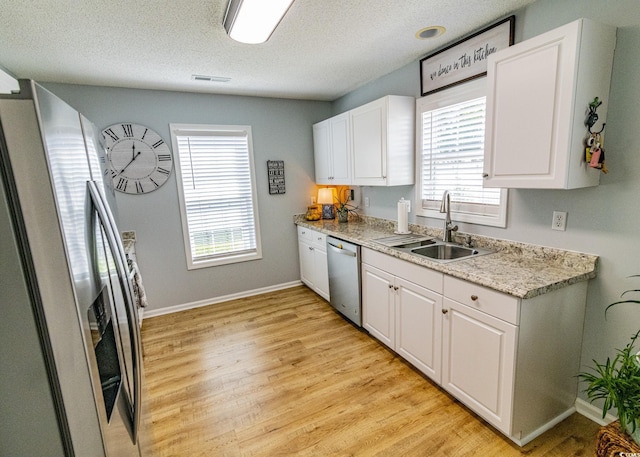 kitchen featuring stainless steel appliances, a sink, visible vents, and white cabinets