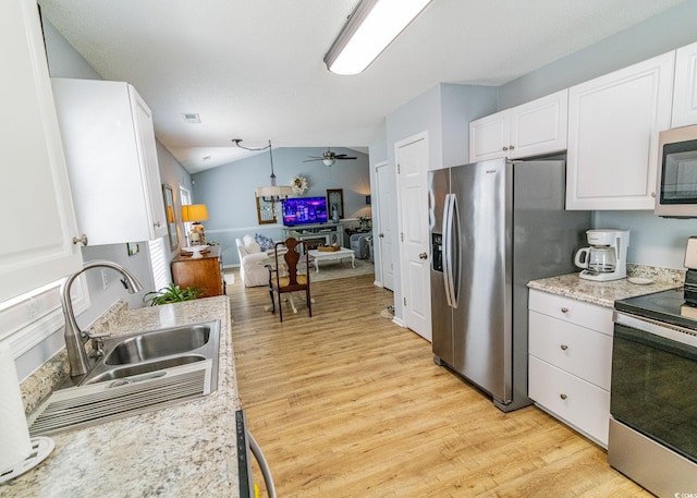 kitchen with stainless steel appliances, a sink, light wood-style floors, vaulted ceiling, and white cabinets