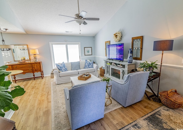 living area featuring a textured ceiling, visible vents, vaulted ceiling, and wood finished floors