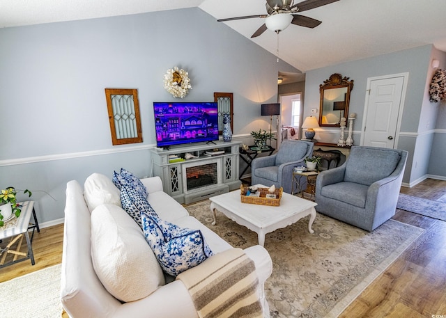 living room featuring lofted ceiling, ceiling fan, wood finished floors, and baseboards