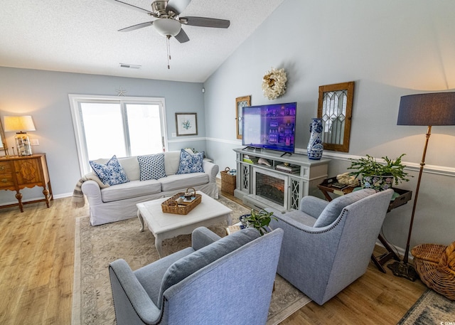 living room with visible vents, light wood-style flooring, vaulted ceiling, a textured ceiling, and ceiling fan