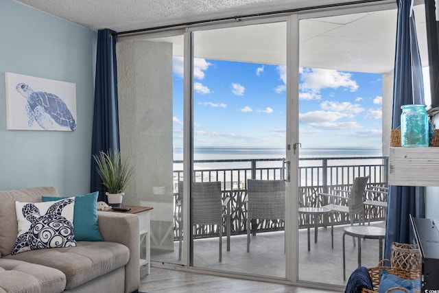 living area with a water view, a healthy amount of sunlight, a wall of windows, and wood finished floors