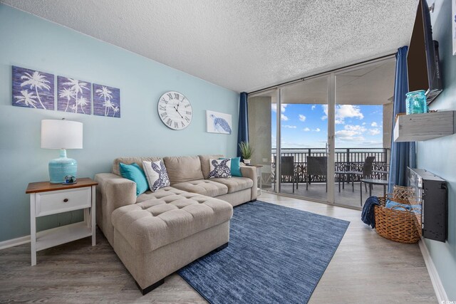 living room with floor to ceiling windows, a textured ceiling, baseboards, and wood finished floors