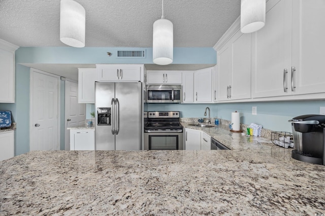 kitchen featuring visible vents, appliances with stainless steel finishes, light stone counters, white cabinetry, and a sink