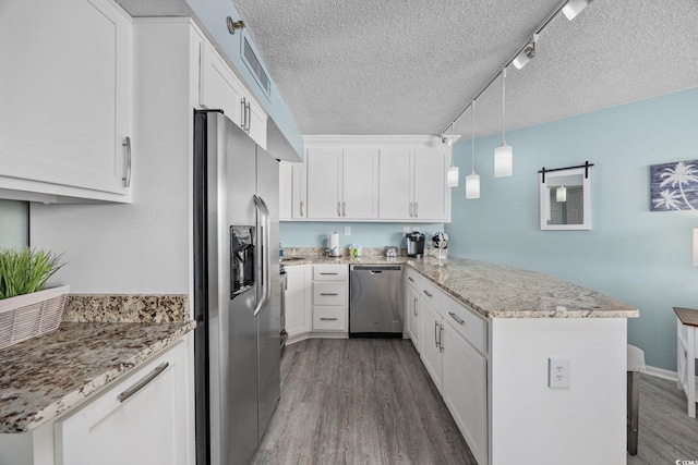 kitchen featuring a textured ceiling, a peninsula, wood finished floors, white cabinetry, and appliances with stainless steel finishes