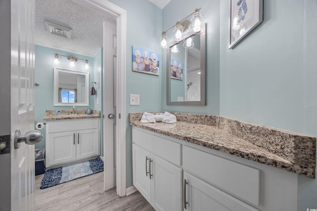 bathroom with a textured ceiling, vanity, and wood finished floors