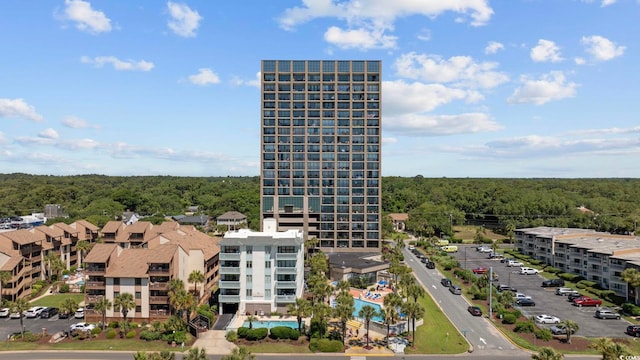 view of building exterior with uncovered parking and a forest view