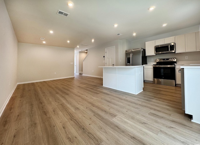 kitchen featuring recessed lighting, stainless steel appliances, light countertops, light wood-type flooring, and a center island