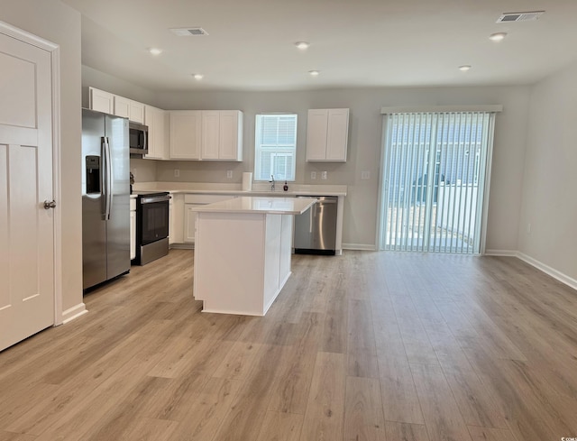 kitchen featuring stainless steel appliances, light wood finished floors, light countertops, and visible vents