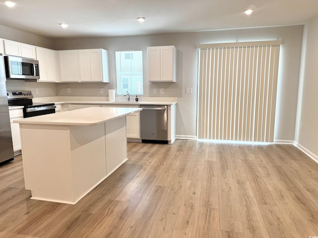 kitchen featuring stainless steel appliances, light countertops, light wood-style flooring, and white cabinetry