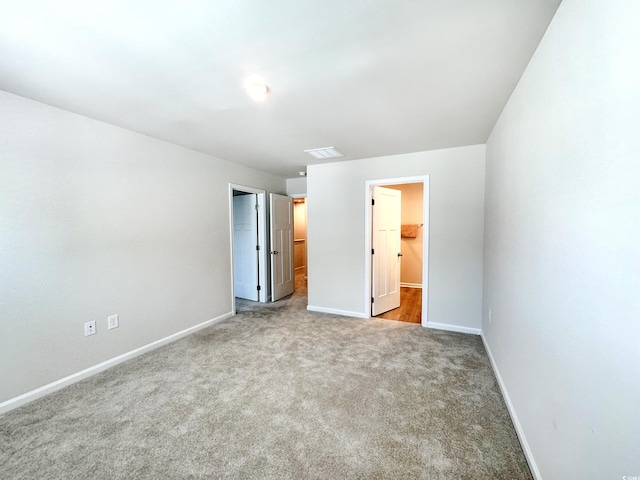 unfurnished bedroom with a closet, carpet flooring, a spacious closet, and baseboards