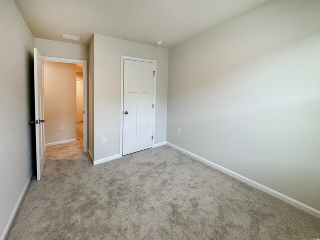 unfurnished bedroom featuring carpet flooring, visible vents, and baseboards