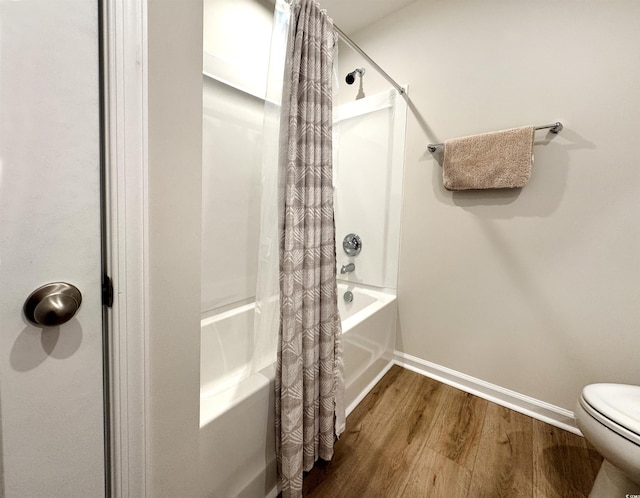 full bathroom with toilet, shower / tub combo, baseboards, and wood finished floors