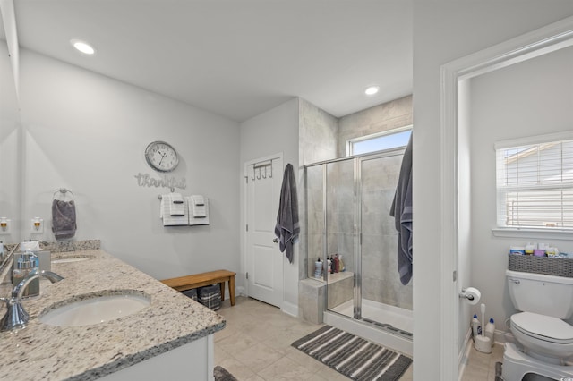 bathroom featuring toilet, a sink, recessed lighting, a shower stall, and double vanity