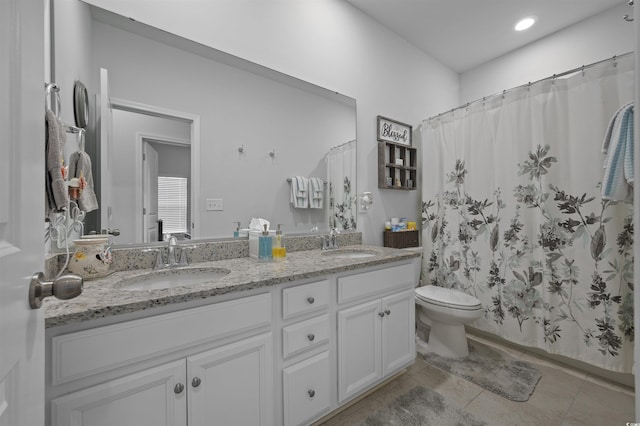 bathroom featuring double vanity, tile patterned floors, toilet, and a sink