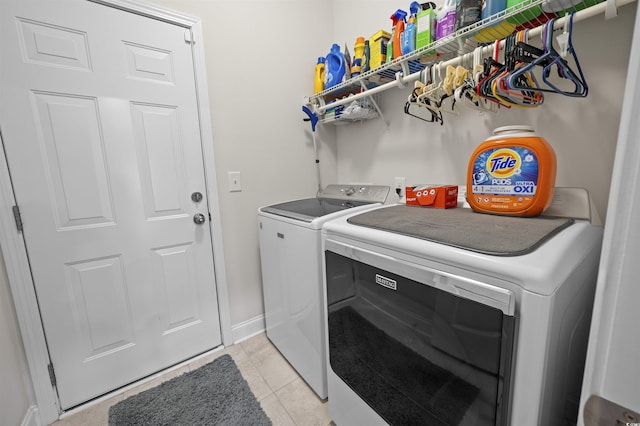 laundry room with laundry area, light tile patterned floors, baseboards, and washing machine and clothes dryer