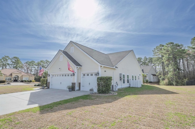 view of home's exterior with central air condition unit, a yard, concrete driveway, an attached garage, and a shingled roof