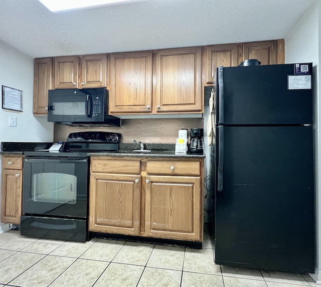 kitchen with light tile patterned floors, dark countertops, black appliances, and a textured ceiling