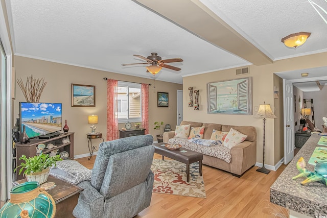 living area with a textured ceiling, light wood-type flooring, visible vents, and crown molding