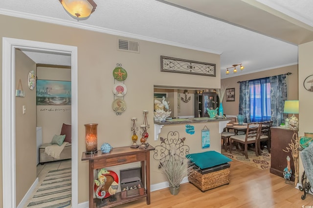 sitting room featuring baseboards, visible vents, ornamental molding, wood finished floors, and a textured ceiling