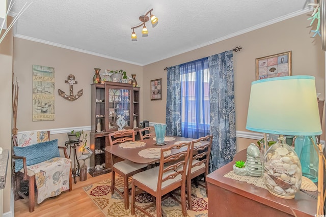 dining space with ornamental molding, a textured ceiling, and wood finished floors