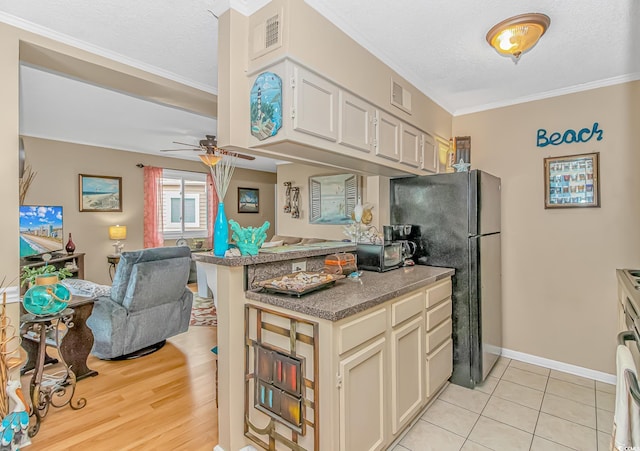 kitchen with visible vents, open floor plan, freestanding refrigerator, a textured ceiling, and crown molding