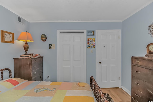 bedroom with light wood finished floors, crown molding, visible vents, and a closet