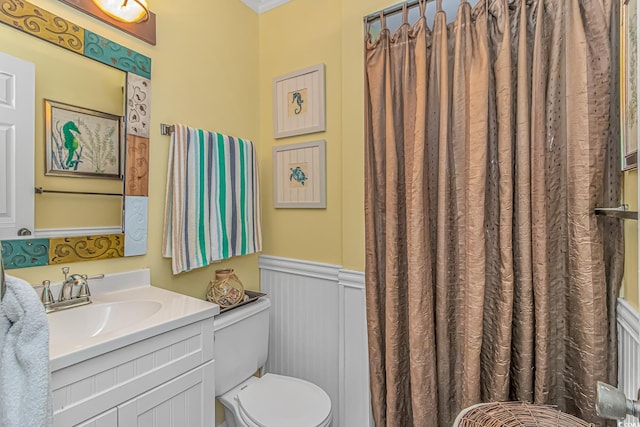 bathroom with toilet, vanity, and wainscoting