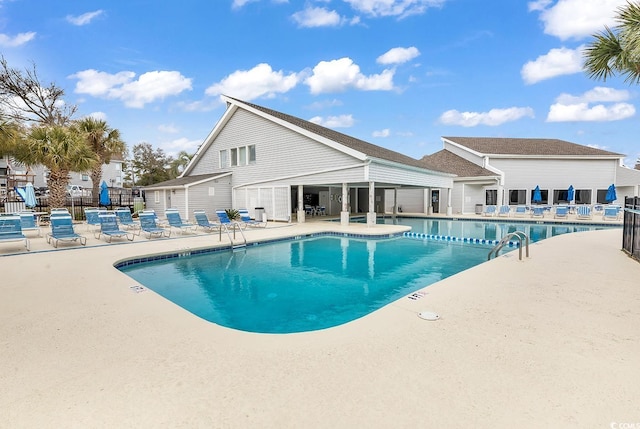 community pool with a patio area and fence