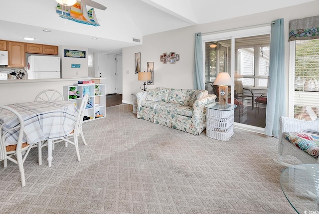 living room with lofted ceiling, ceiling fan, visible vents, and light colored carpet