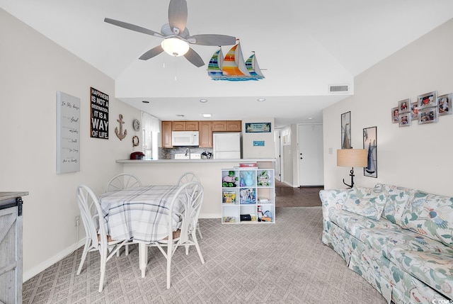 dining area with visible vents, light carpet, vaulted ceiling, ceiling fan, and baseboards