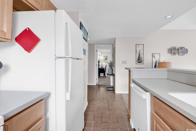 kitchen with a textured ceiling, light brown cabinets, white appliances, light countertops, and tile patterned floors