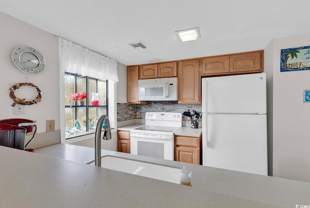 kitchen with white appliances, a sink, visible vents, light countertops, and decorative backsplash