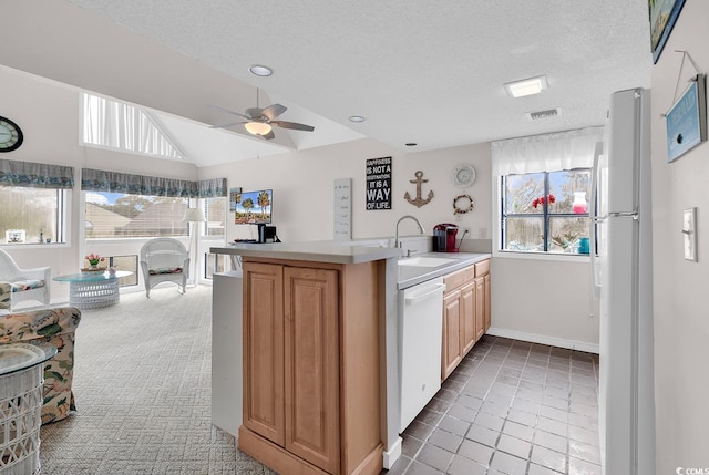 kitchen with white appliances, vaulted ceiling, light countertops, a textured ceiling, and a sink